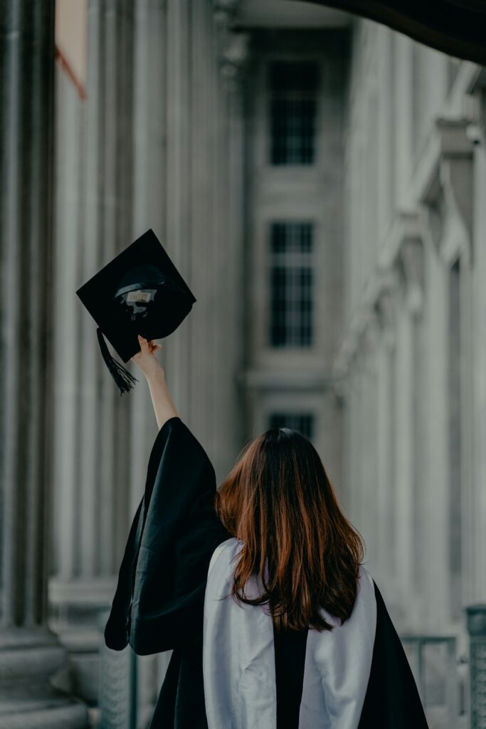 Graduanda con toga frente a un edificio universitario