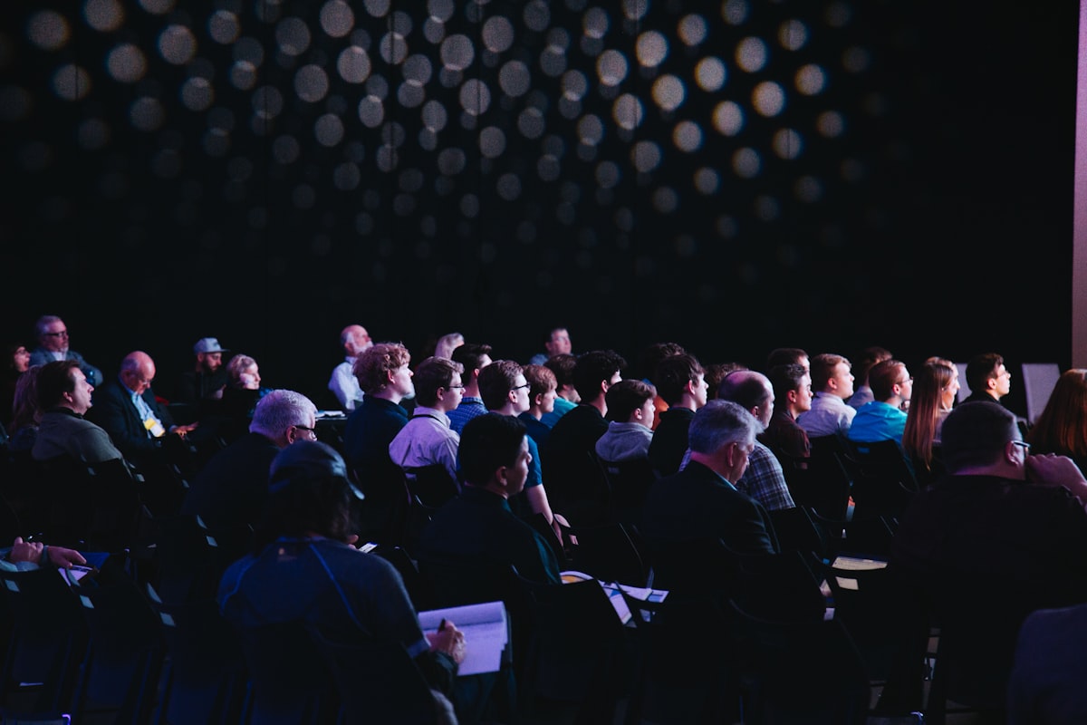 Asistentes en un evento corporativo en sala oscura