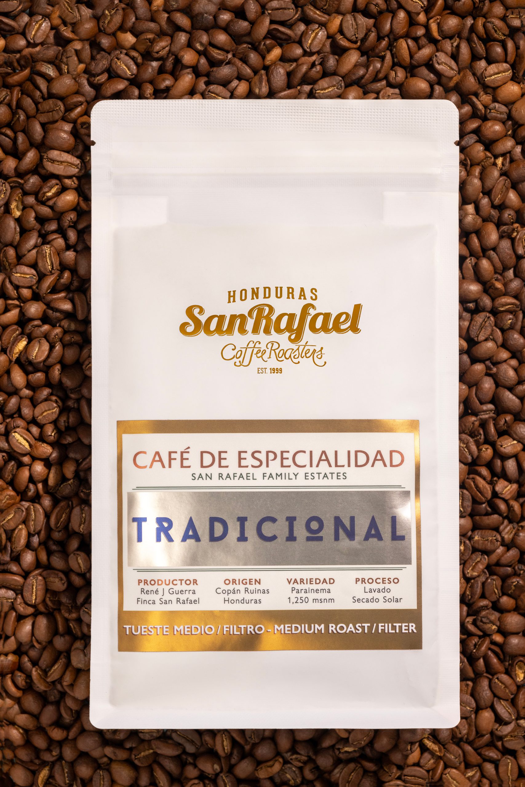 Bolsa blanca de café Tradicional de Café San Rafael sobre granos de café tostado