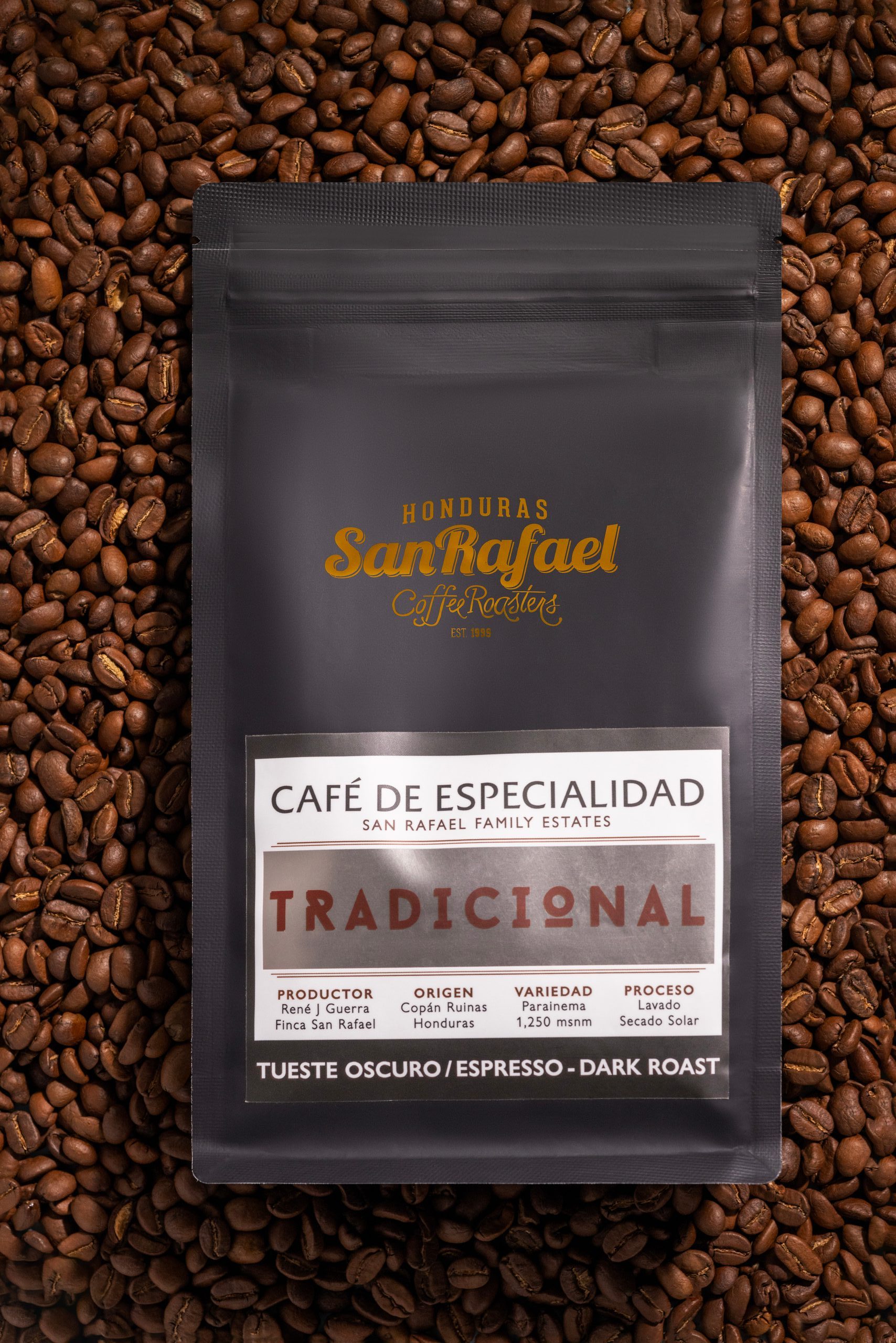 Vista cenital de una bolsa negra de café Tradicional de Café San Rafael sobre granos tostados