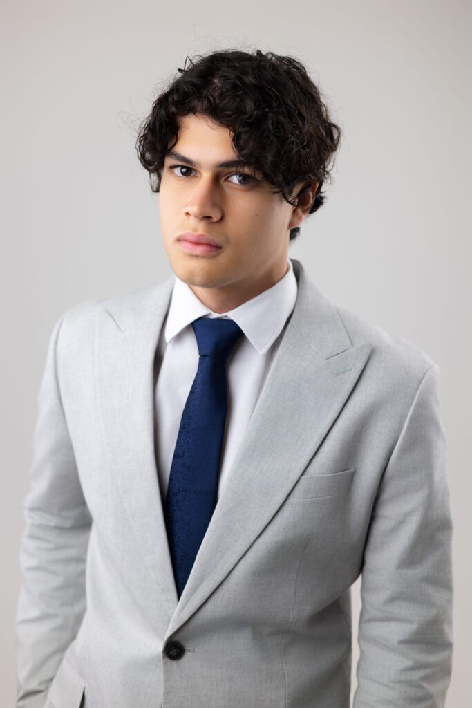 Iván con saco gris y corbata azul, retrato senior formal, San Pedro Sula